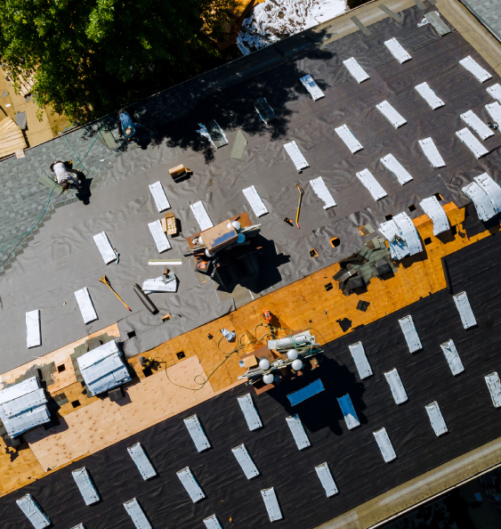 About the company Aerial view of workers installing roofing materials in Colorado Springs, showing tools, supplies, and roof restoration in progress.