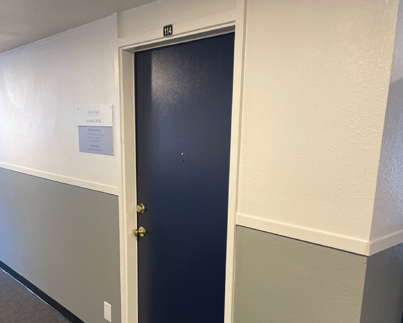 A blue door labeled 114 with two gold locks, ideal for Colorado Springs exterior home restoration or roofing projects, in a hallway.